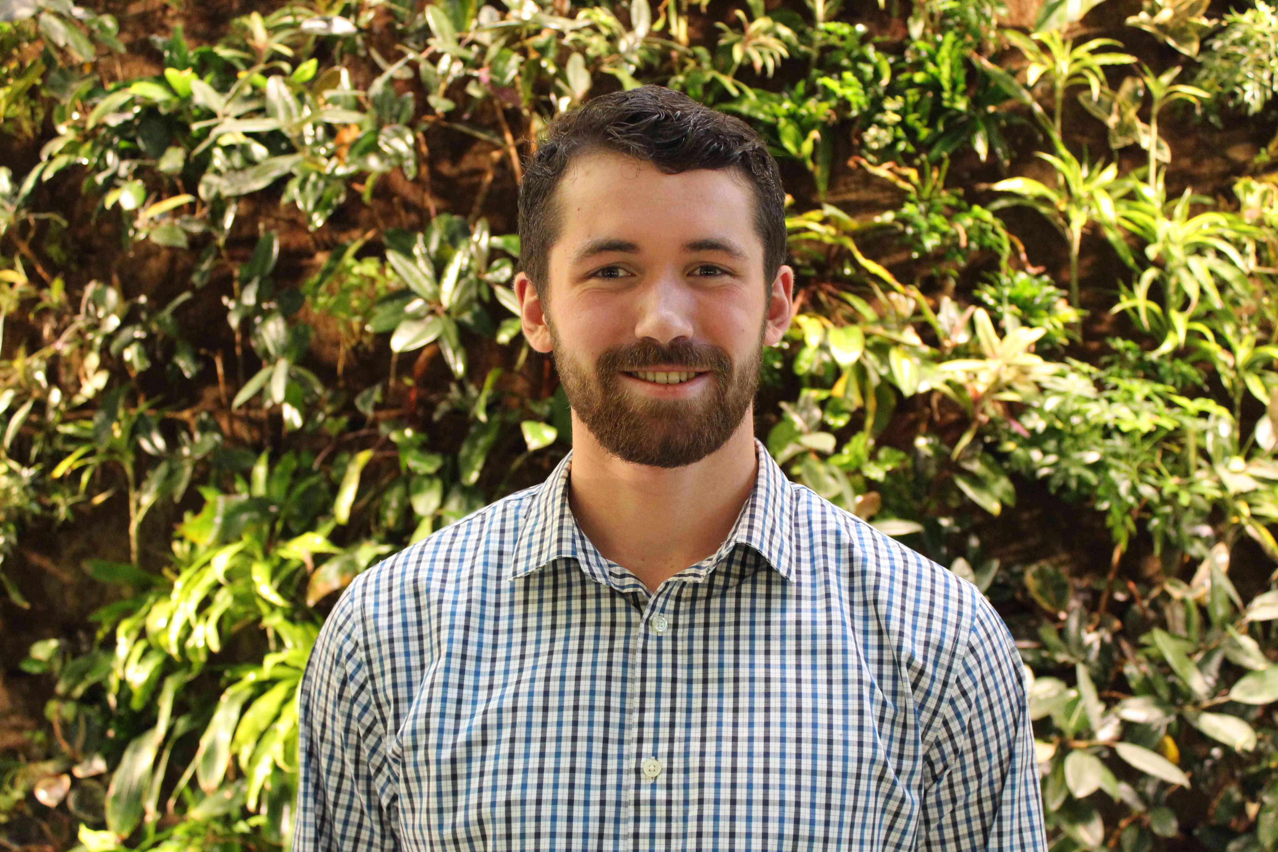 Image of ian in a button up with a bush in the background